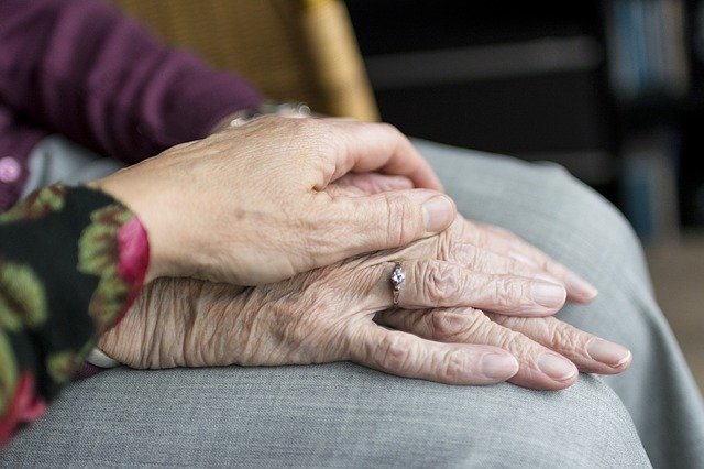 Une main de femme posée sur la main les mains réunies d'une femme âgée